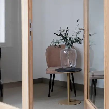a glass vase with a plant on a table in a room