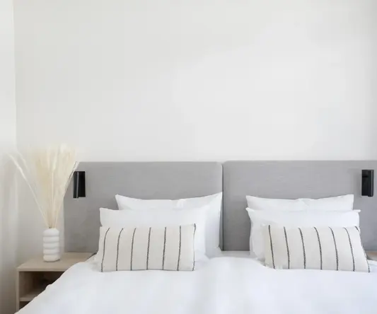 a bed with white sheets and pillows