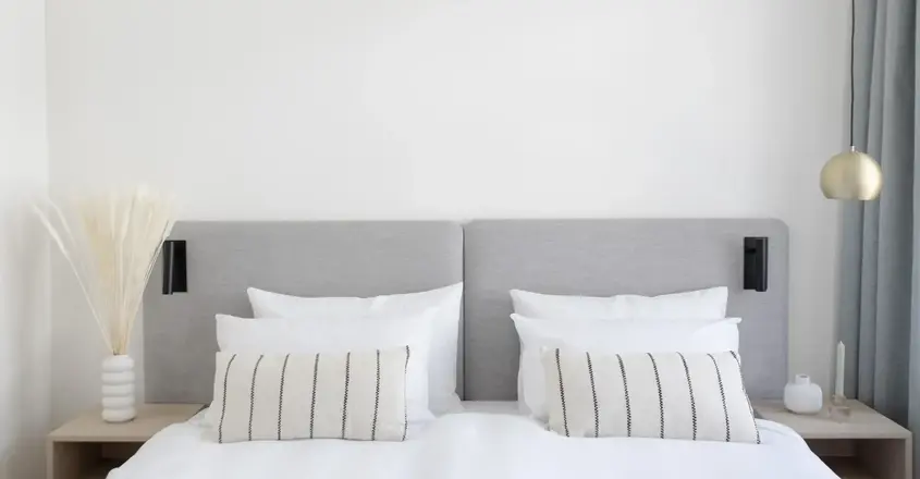 a bed with white sheets and pillows