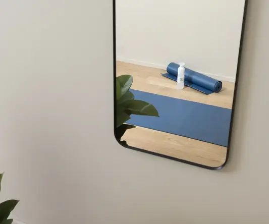 a mirror of a yoga mat and a bottle on a wooden floor