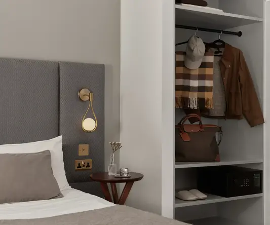 a bed with a headboard and a shelf with clothes on it