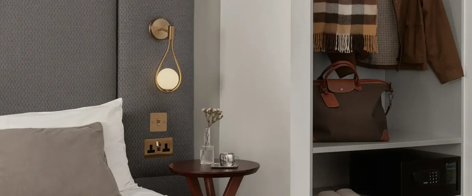 a bed with a headboard and a shelf with clothes on it