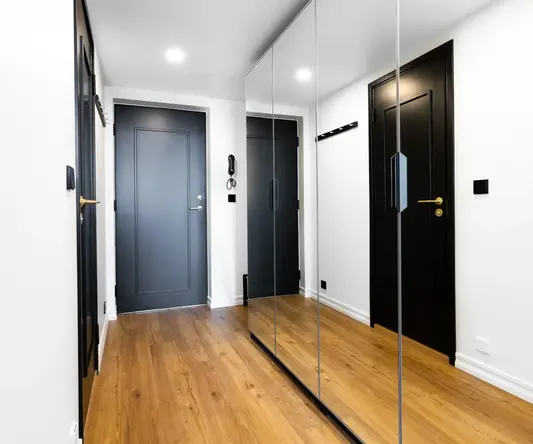 a hallway with black doors and a wood floor