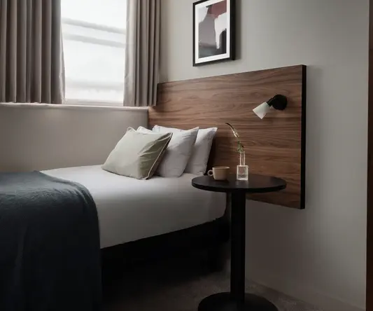 a bed with a wood headboard and a lamp