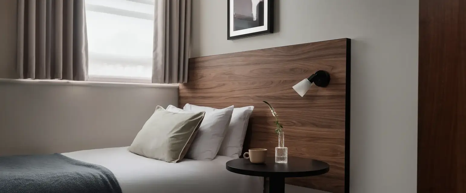 a bed with a wood headboard and a lamp