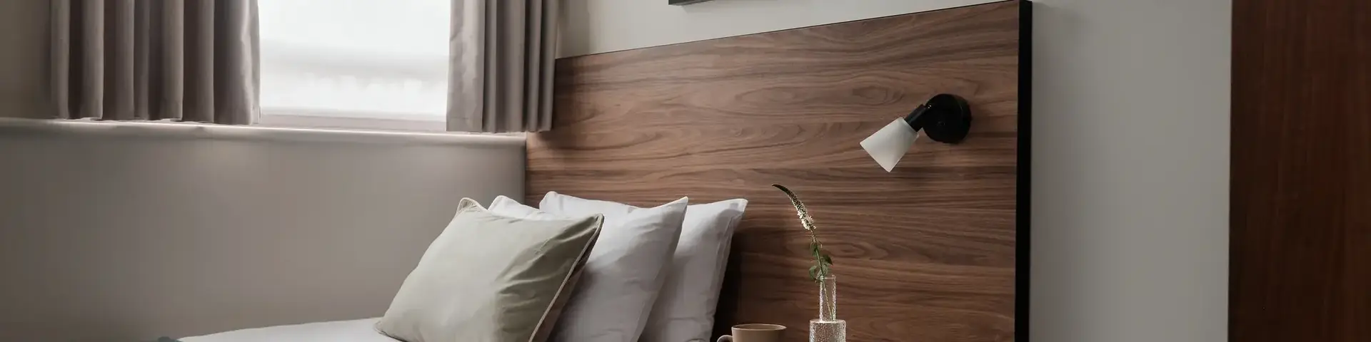 a bed with a wood headboard and a lamp