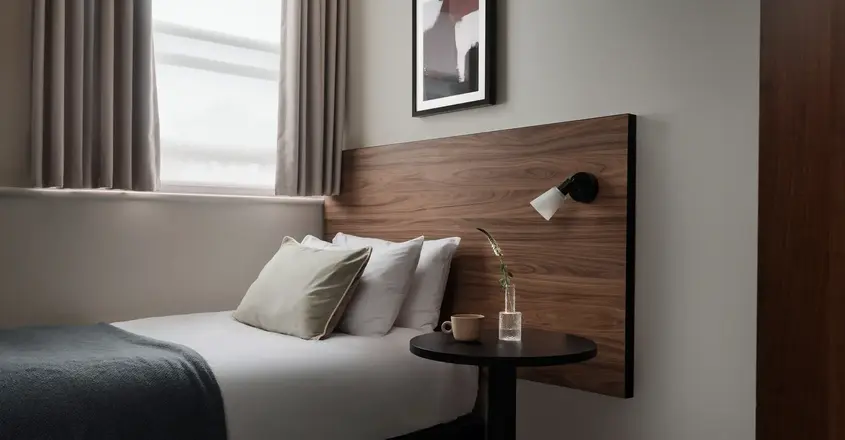 a bed with a wood headboard and a lamp