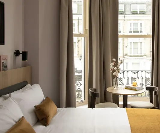 a bed with a table and chairs in a room with curtains