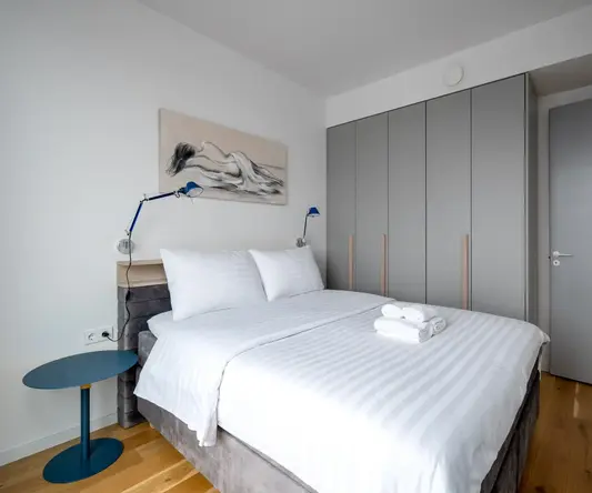 a bed with white sheets and a blue table