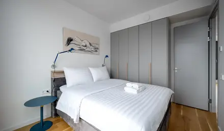 a bed with white sheets and a blue table