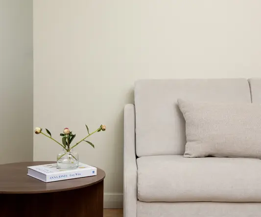 a couch with a pillow and a vase of flowers on a table