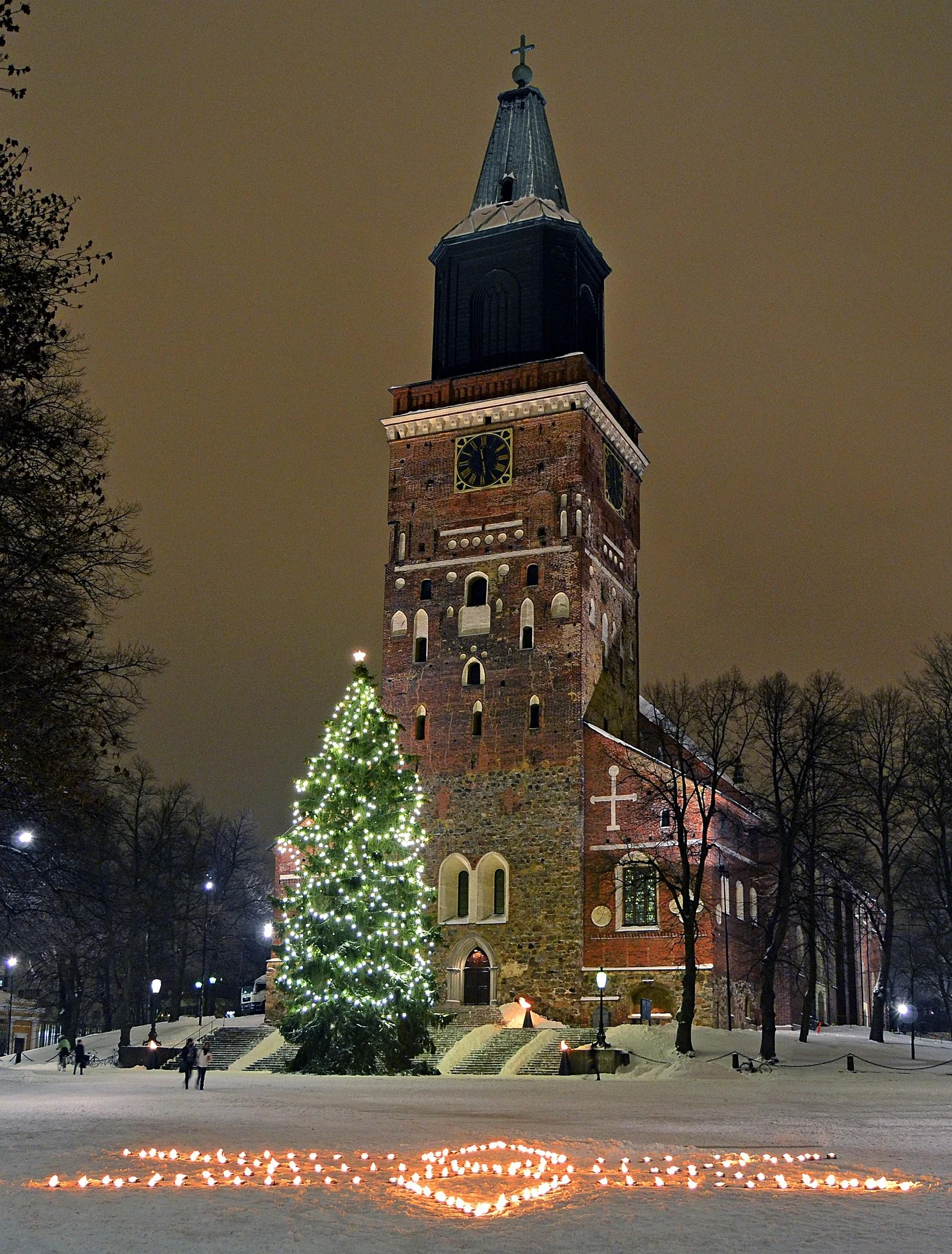 Turku Cathedral with a lit Christmas tree and candles glowing in the snow