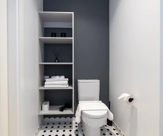 a toilet with shelves and a black and white checkered floor