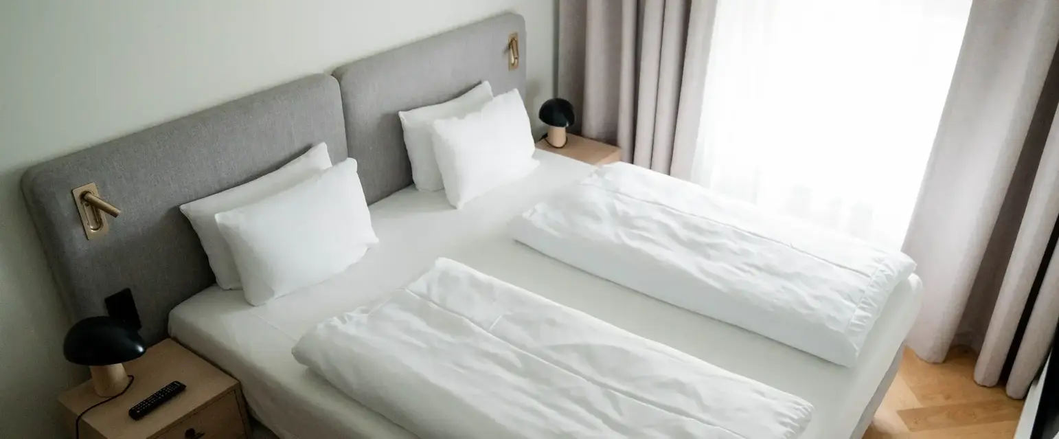 a bed with white sheets and pillows