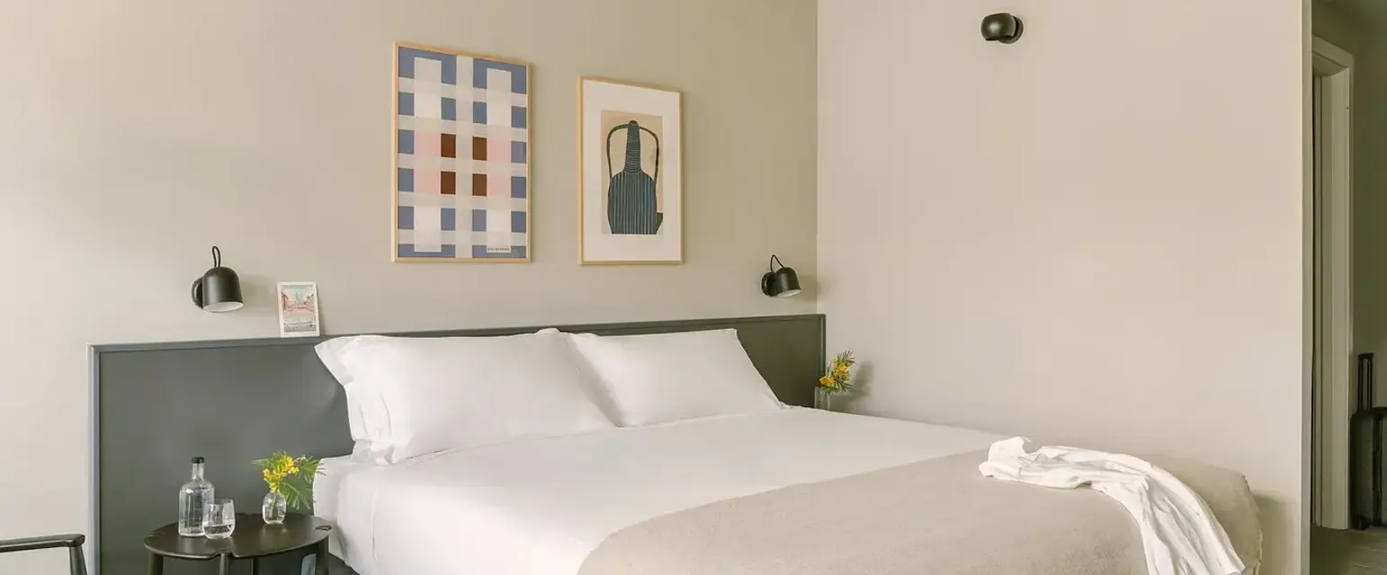 a bed with white sheets and pillows