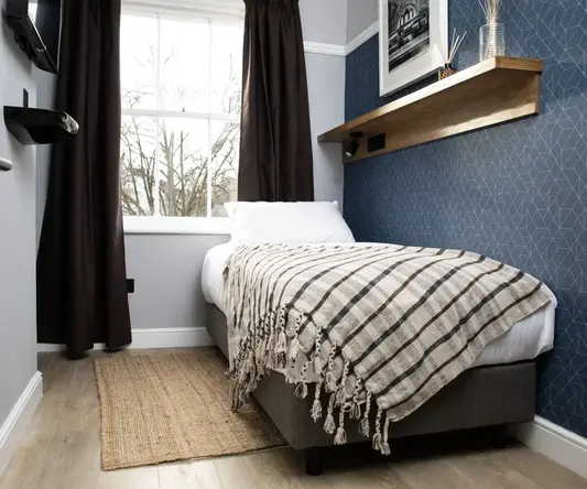 a bed with a blanket and a shelf in a room