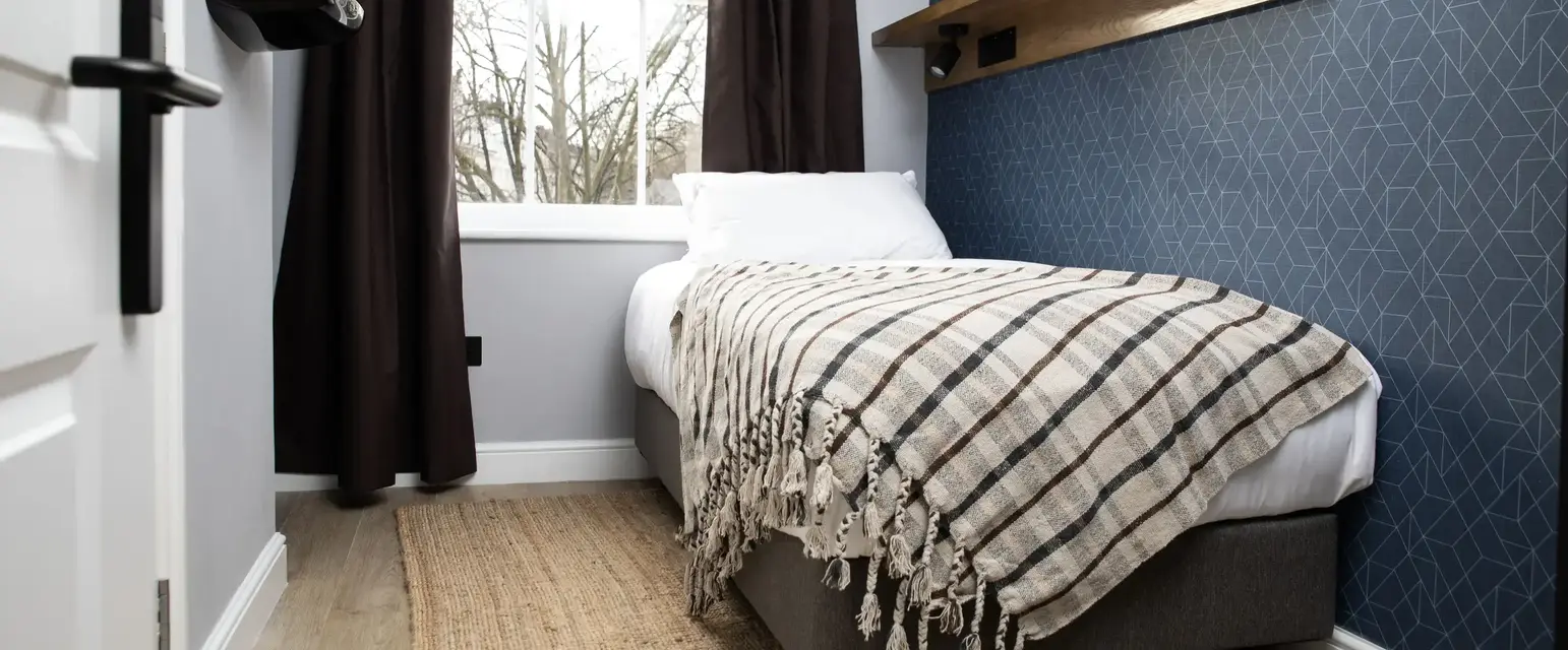 a bed with a blanket and a shelf in a room