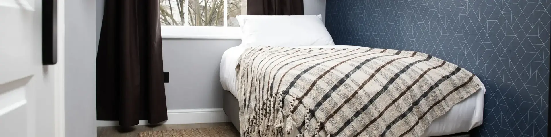 a bed with a blanket and a shelf in a room