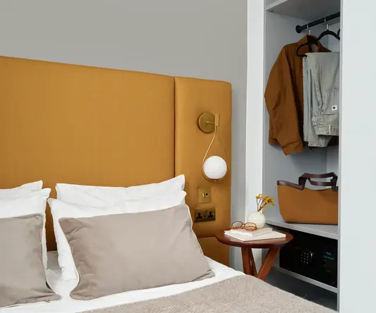 a bed with a headboard and a table with clothes