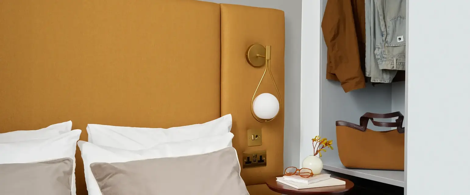 a bed with a headboard and a table with clothes