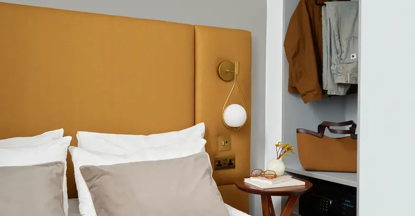 a bed with a headboard and a table with clothes