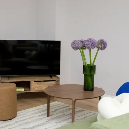 a vase of purple flowers on a table in a living room