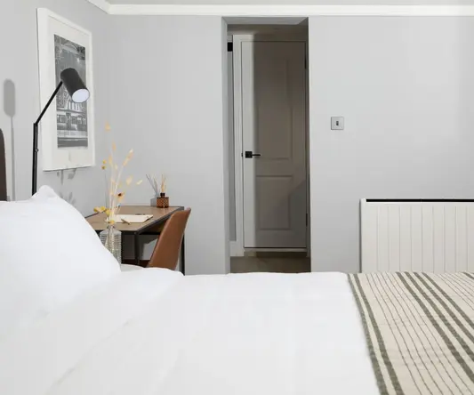 a bed with a striped blanket and a desk in a room