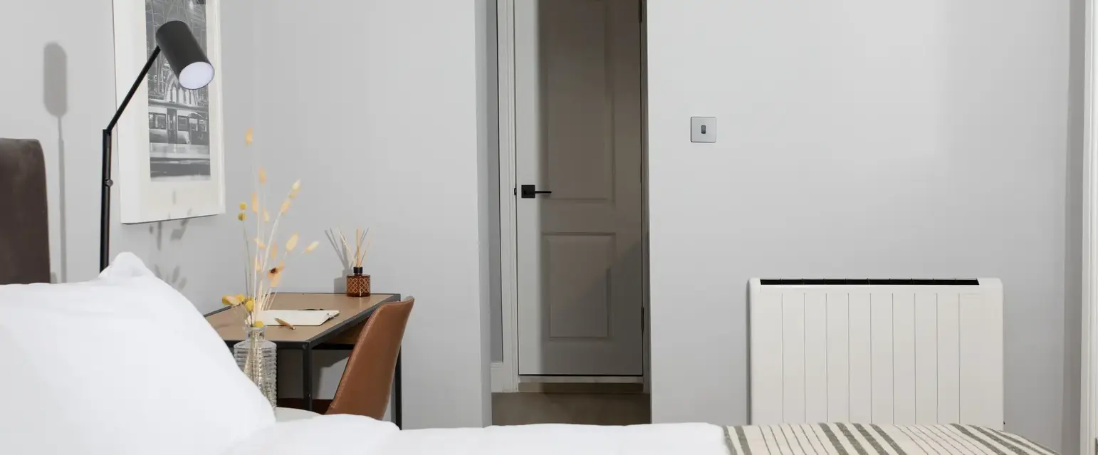 a bed with a striped blanket and a desk in a room