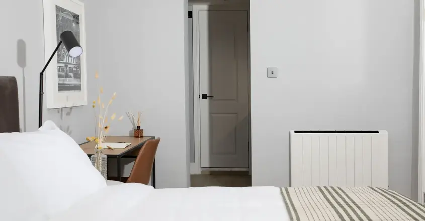 a bed with a striped blanket and a desk in a room