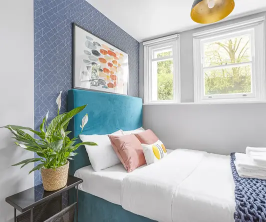 a bed with pillows and a plant in a room