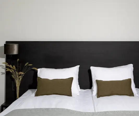 a bed with white pillows and brown pillows