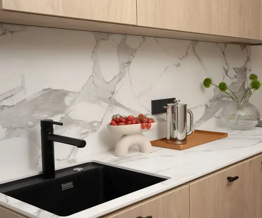 a kitchen counter with a sink and a bowl of tomatoes