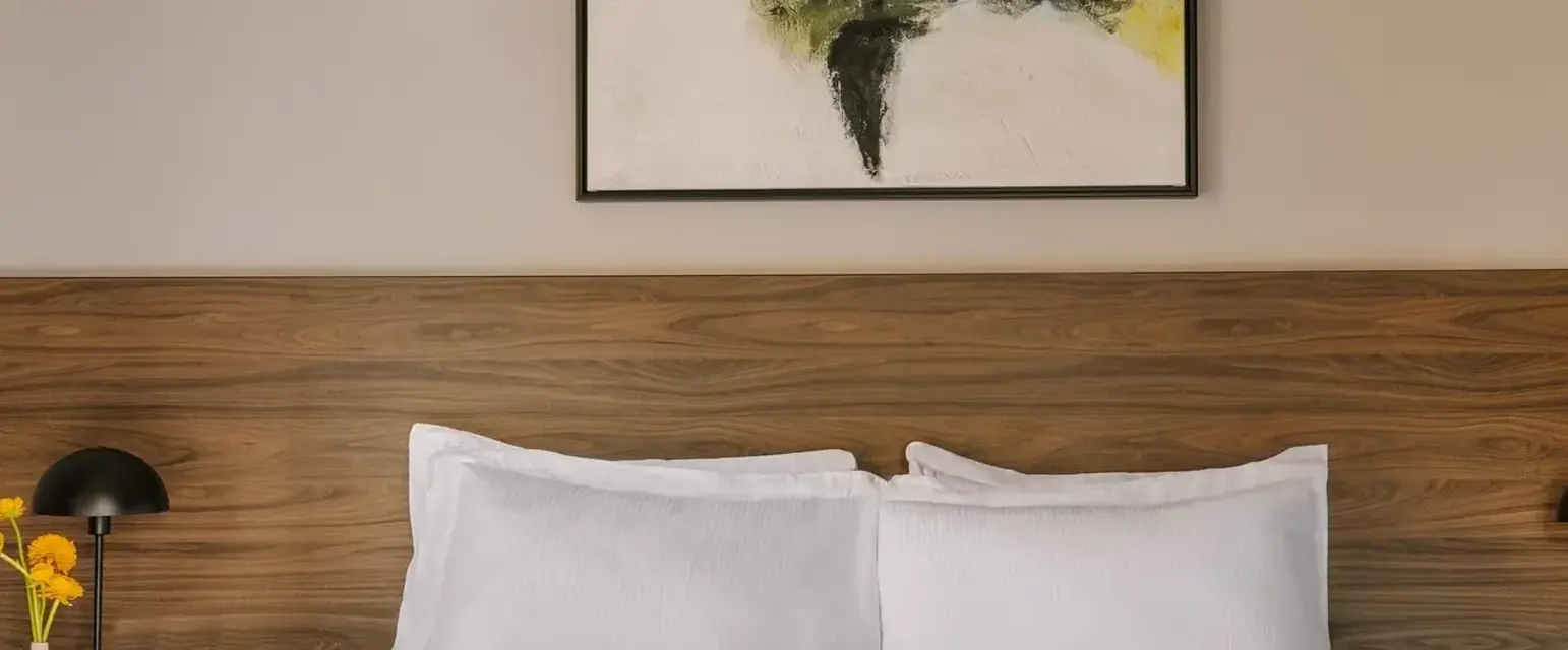a bed with white sheets and a painting on the wall