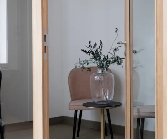 a glass vase with a plant on a table in a room