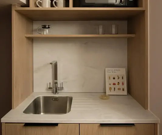 a kitchen with a microwave and a book on the shelf
