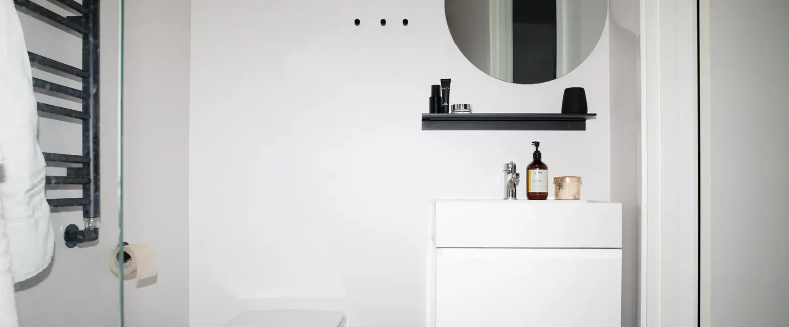 a bathroom with a round mirror and a toilet