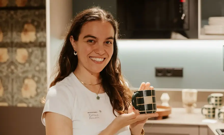 a woman holding a cup in a kitchen