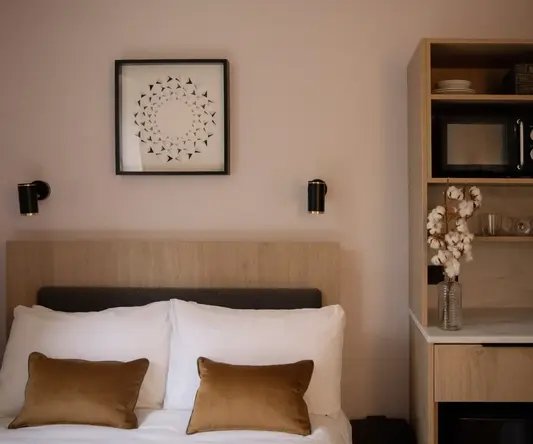 a bed with pillows and a shelf with a picture on the wall