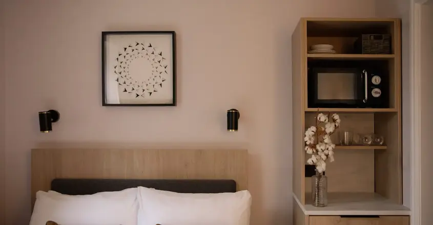 a bed with pillows and a shelf with a picture on the wall