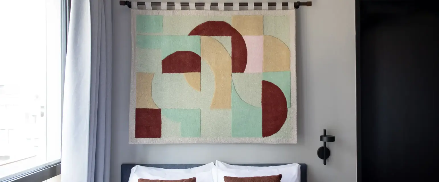 a bed with pillows and a piece of art on the wall