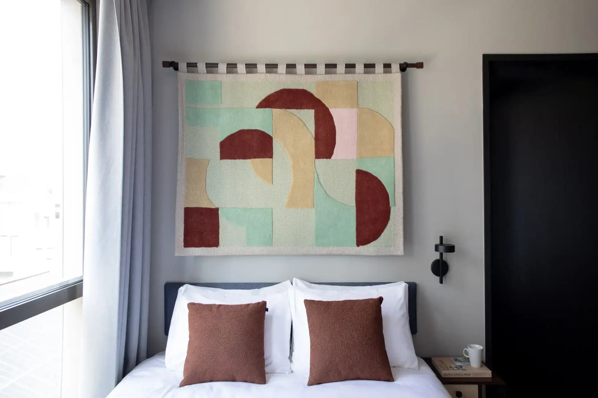 a bed with pillows and a piece of art on the wall