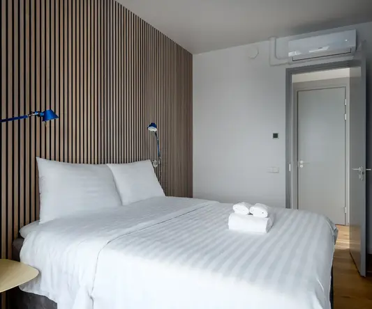 a bed with white sheets and blue lamps