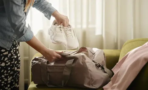 a woman putting shoes on a bag