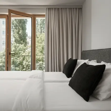 a bed with white sheets and black pillows