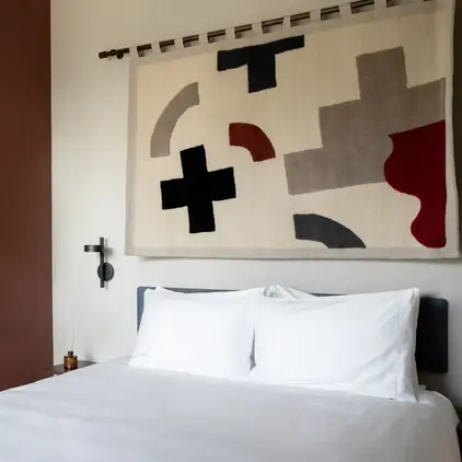 a bed with a white sheet and a black television above it