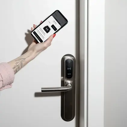 a hand holding a phone next to a door handle