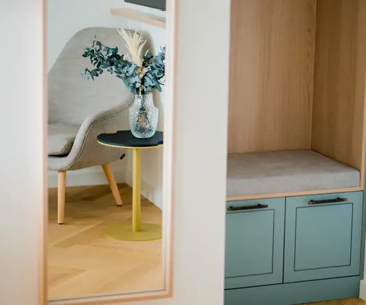 a mirror of a room with a vase of flowers