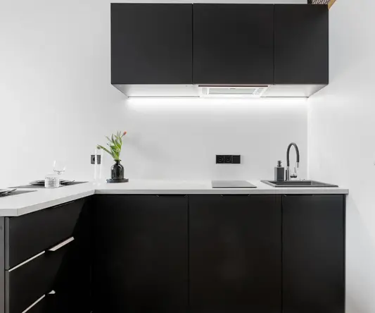 a kitchen with black cabinets and white counter tops