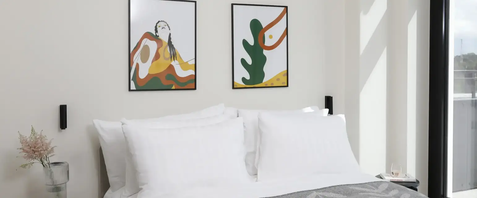 a bed with pillows and a picture on the wall