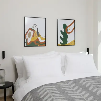 a bed with pillows and a picture on the wall